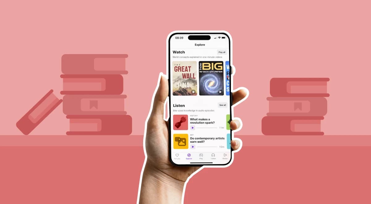 Hand holding a smartphone showing the Nibble app's Explore screen with Watch and Listen microlearning modules, pink background with illustrated stacks of books on both sides